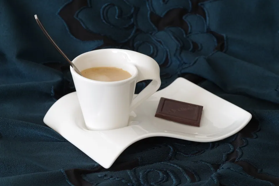 En hvid espressokop på underkop mod blåt stof